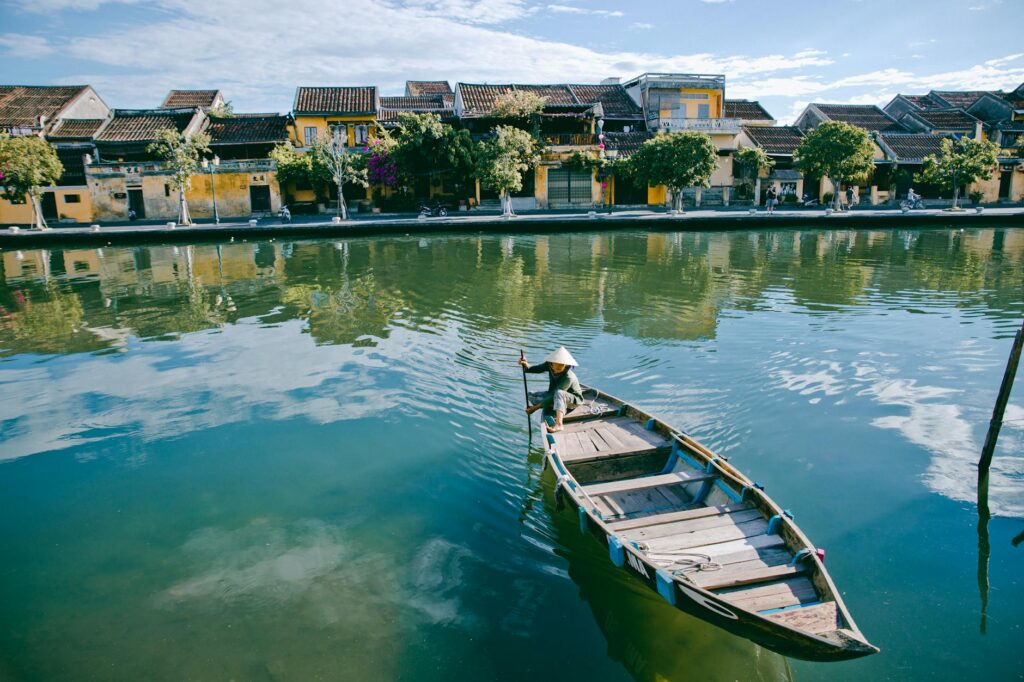 pexels-photo-2796627-2796627 Peaceful scene of a traditional boat on the serene river in Hội An, Vietnam, showcasing historic architecture.