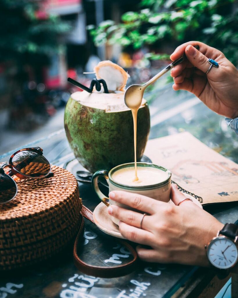 pexels-photo-4457107-4457107 Person enjoying creamy coffee with coconut outdoors, evoking relaxation and a tropical vibe.